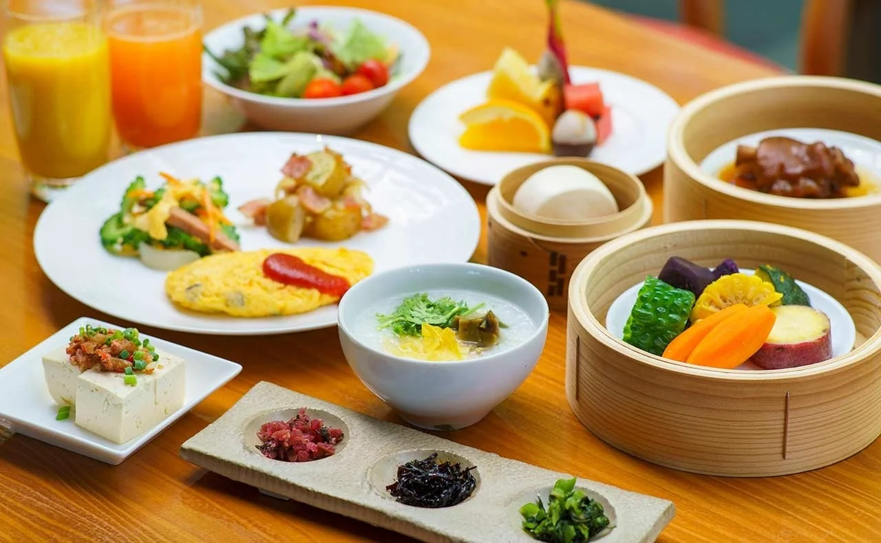 朝食、ブッフェ、バイキング、和食、洋食、中華料理、多国籍料理、料理、食事、ホテル朝食、旅館朝食、健康的な食事、ヘルシー、フルーツ、野菜、お粥、オムレツ、豆腐、点心、蒸し料理、ドリンク、ジュース、テーブル、盛り合わせ、豪華、美味しい