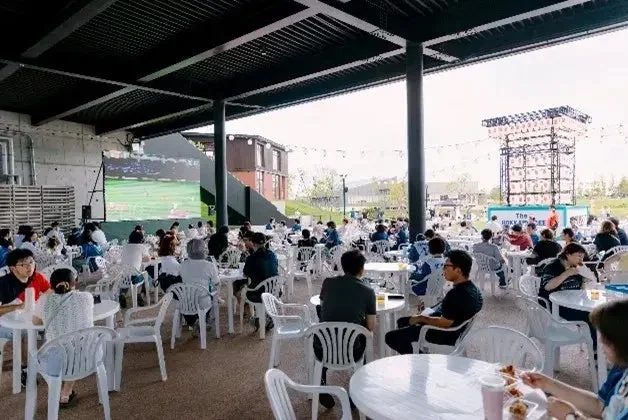 屋外テラス席でスポーツ観戦を楽しむ人々