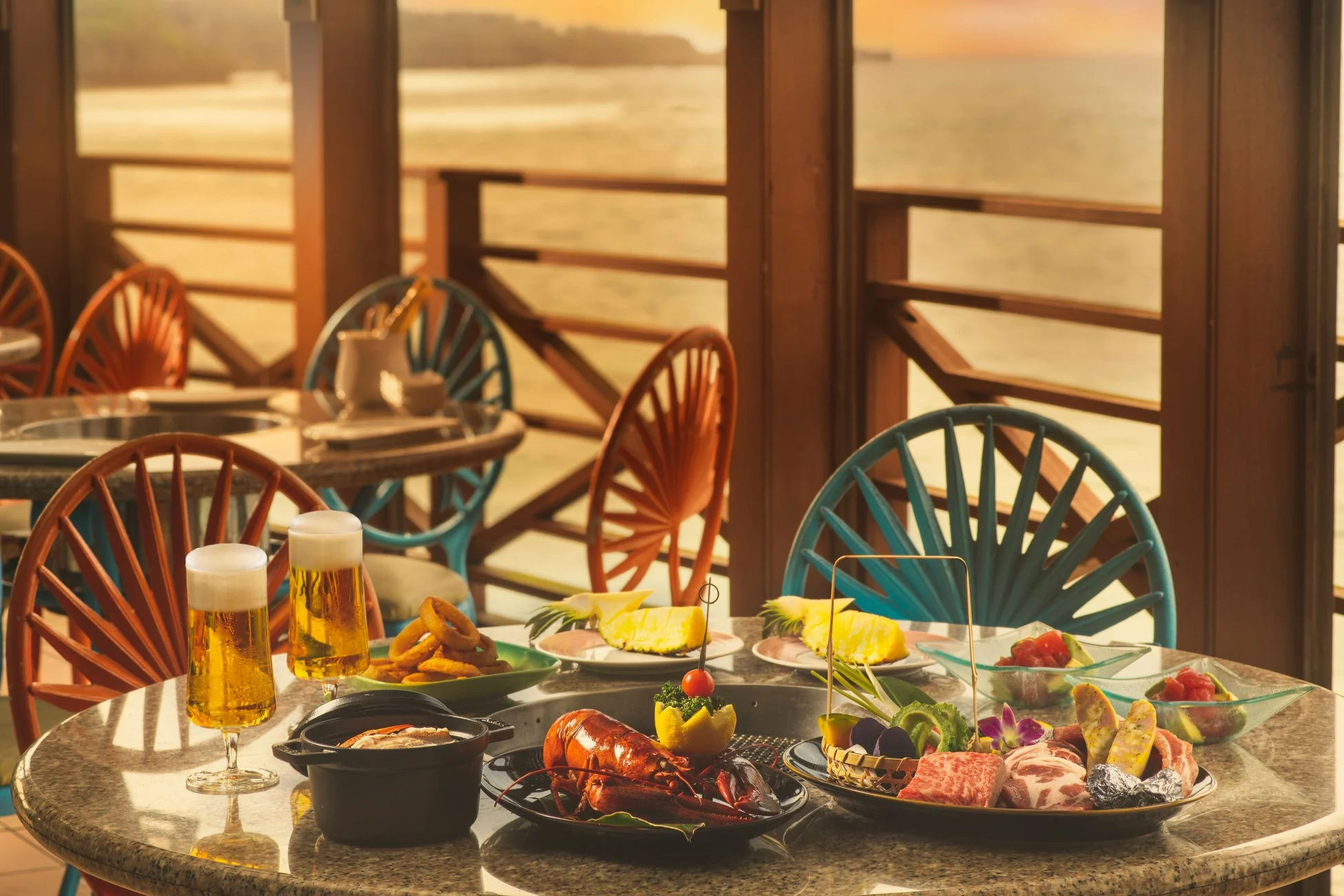 夕焼けの海を望むテラス席での豪華な食事